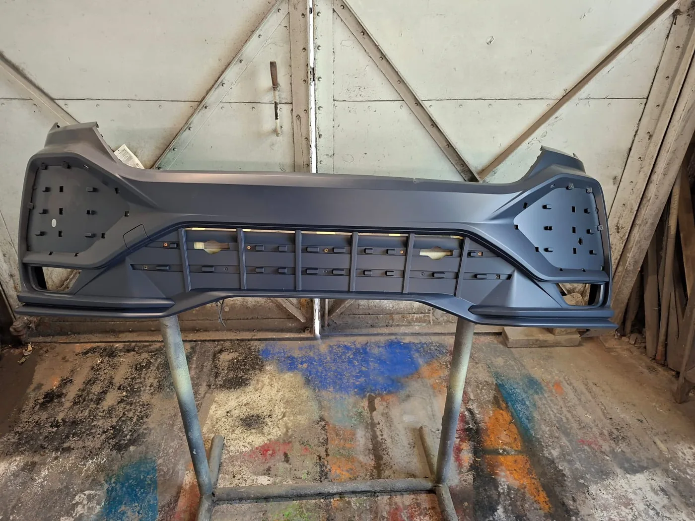 Bare bumper on a stand, stripped and prepped for paint