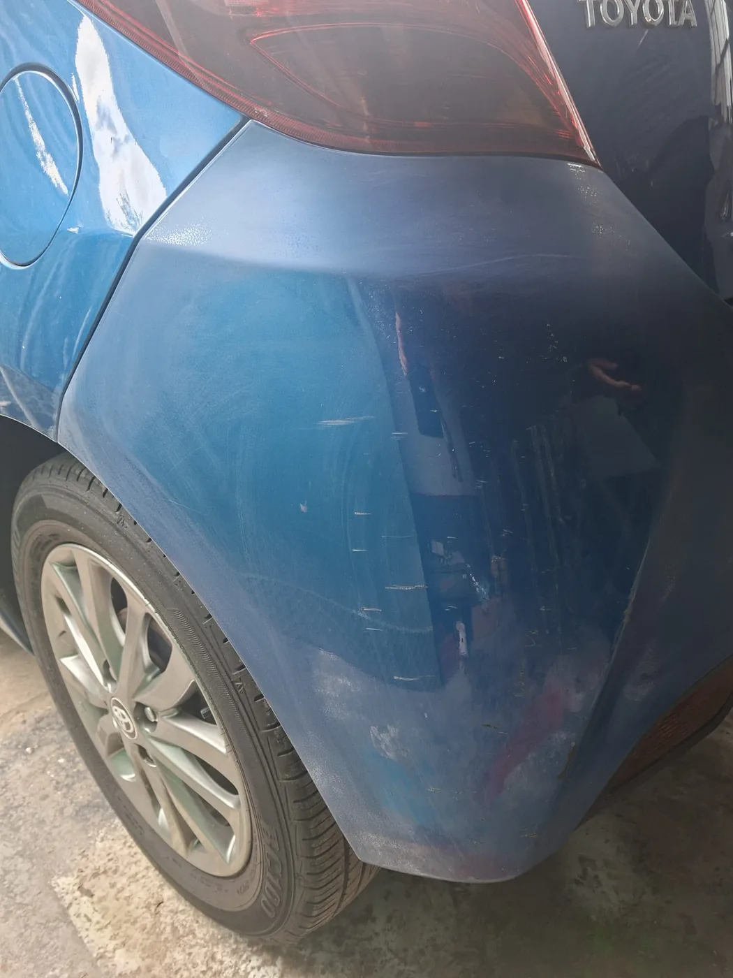 Scuffed and scratched rear quarter on a blue hatchback, booked in for repair