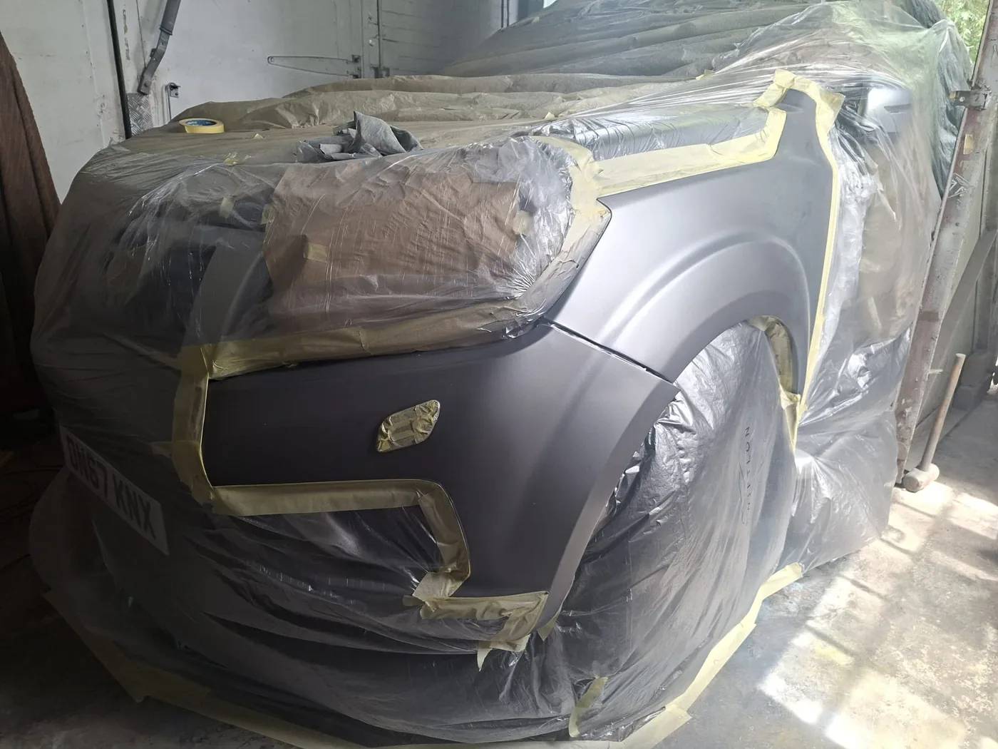 Vehicle fully masked and sheeted in the unit, ready to be sprayed