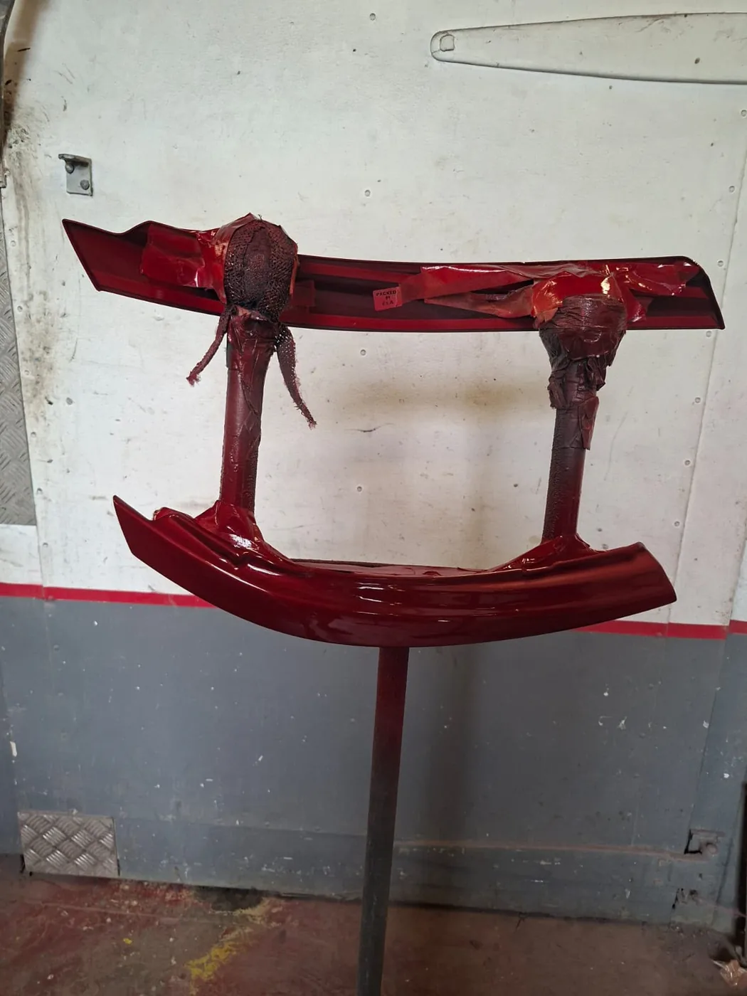 Freshly sprayed red bumper components drying on a stand