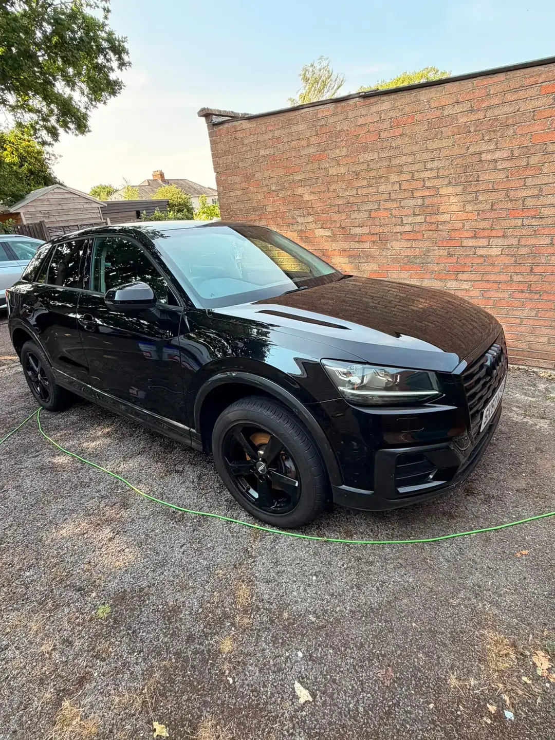 Audi Q2 front three quarter against a brick wall, paintwork reflecting like glass