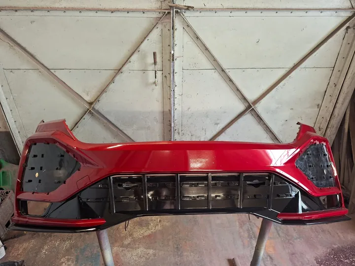 Front bumper freshly resprayed in deep gloss red after repair